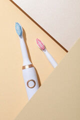 Electric toothbrushes and paper on beige background, top view