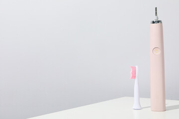 Electric toothbrush on table on gray background, space for text