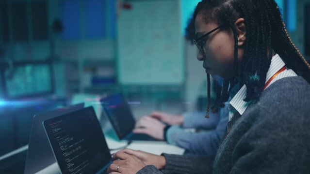 Focused African American woman testing software code with a coworker in office