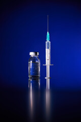 Injection with COVID19 vaccine vial in blue studio