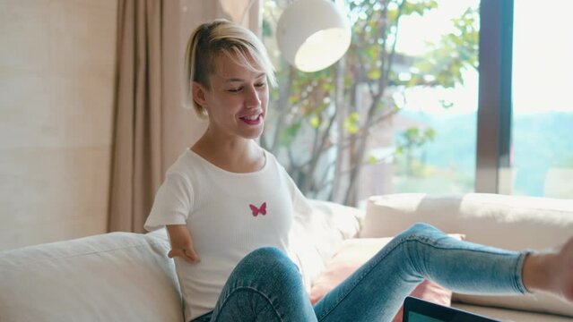 Woman without arms holds a cup of coffee using her legs while spending time with her family at home