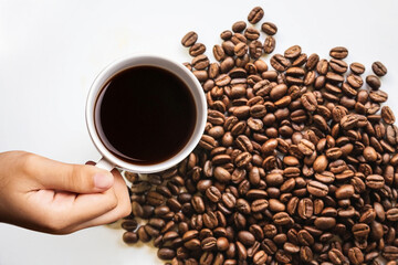 Hand holding white coffee cup with coffee beans