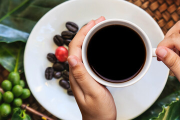 Hand holding white coffee cup with coffee beans