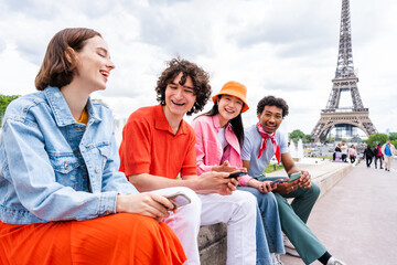 Group of young happy friends visiting Paris and Eiffel Tower - Multiethnic teens bonding outdoors and having fun sightseeing the city