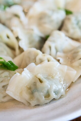 Fototapeta na wymiar Fresh, delicious boiled garlic chives dumplings, jiaozi in white plate on wooden table background.