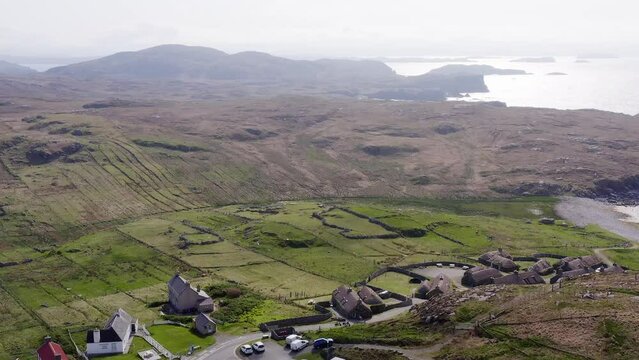 Wide angle drone shot of the Gearrannan Blackhouse Village on the Isle of Lewis, part of the Outer Hebrides of Scotland. Stone blachouses are visible on the hills.