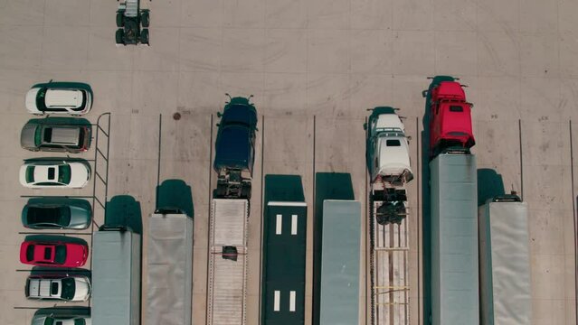 beautiful aerial of a red semi bobtail backing up to a reefer - dry van trailer to hook it up. Proccess of coupling a tractor and trailer. Parking yard with other tractors and trailers parked. America
