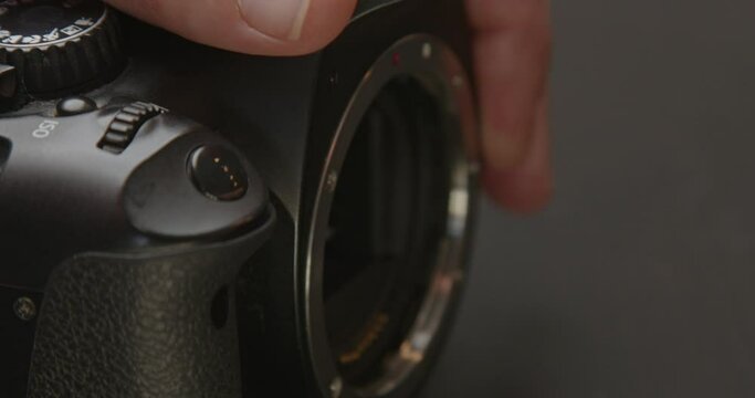 Hand removing lens from digital DSLR photo camera