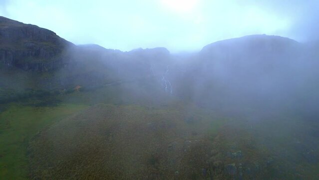 Orbit view of the entrance to the lagunas pampeadas of the cajas national park in cuenca ecuador made from a drone in the morning hours flying through the white clouds of the park