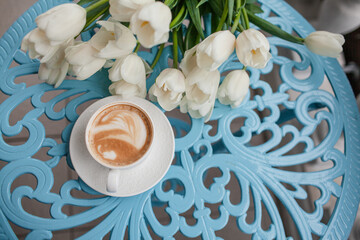 Beautiful woman drressed biege elegant suit sit in cafe and drink the cup of coffee. The plus size woman holding a bouquet of whine flowers. Happy overweight model
