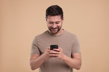 Happy man using smartphone on beige background