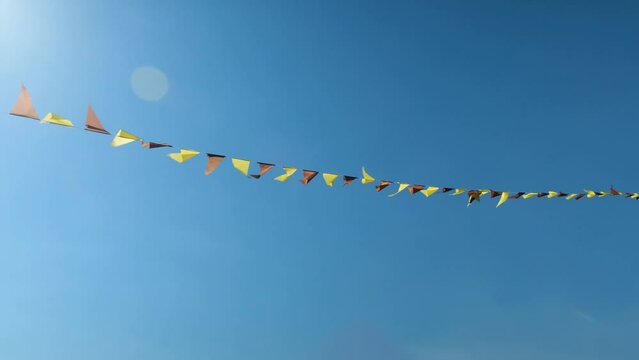 Colorful flags hanging on the background of blue sky as festive decorations for outdoor party.