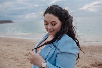 beautiful plus size woman walking in the beach against the sea. . The overweight model wearing style blue jacket  and jeans