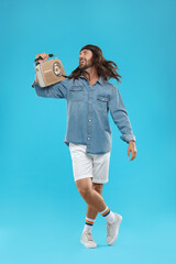 Stylish hippie man with retro radio receiver on light blue background