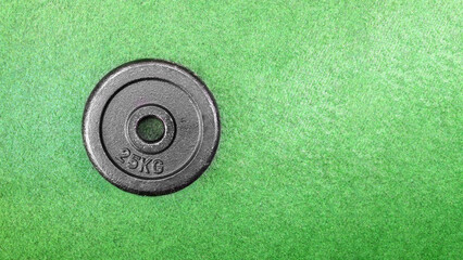 Top view of a 25 kg dumbbell weight on a green grass floor background