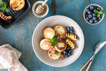Cottage cheese pancakes, cheesecakes, ricotta fritters with fresh blueberries, currants and peaches