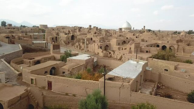 Mud brick village down town rural area adobe house buildings mosque and ruins of ancient civilization local people life in desert wide view of horizon cloudy sky summer sun in saudi arabia yazd iran
