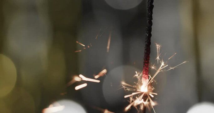 Video of close up of sparkler with bokeh and copy space on black background