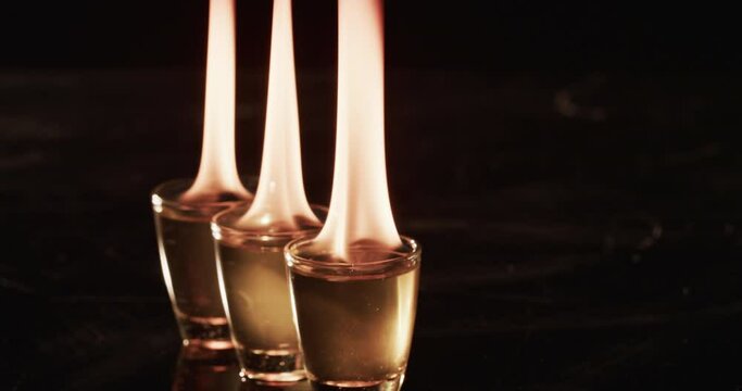 Video of lit alcohol in glasses with yellow fire flames and copy space on black background