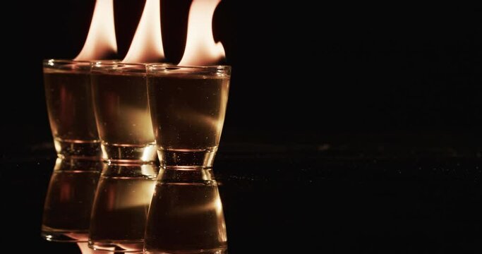 Video of lit alcohol in glasses with yellow fire flames and copy space on black background