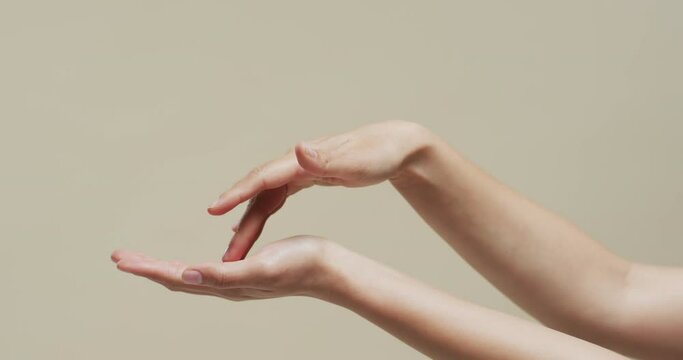 Hands of asian woman on beige background with copy space, slow motion