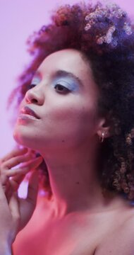 Vertical video of biracial woman with dark hair in blue and pink light, slow motion