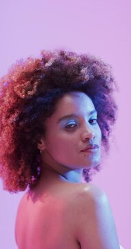 Vertical video of biracial woman with dark hair in blue and pink light, slow motion