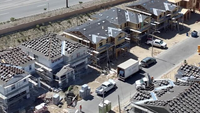 Aerial view dolly across new build housing property development rooftops, looking down over construction site