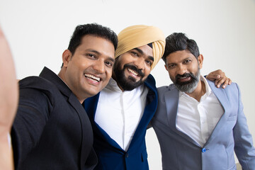 Group of positive indian business colleagues wearing suit having fun looking at camera isolated on white studio background. Corporate Concept.