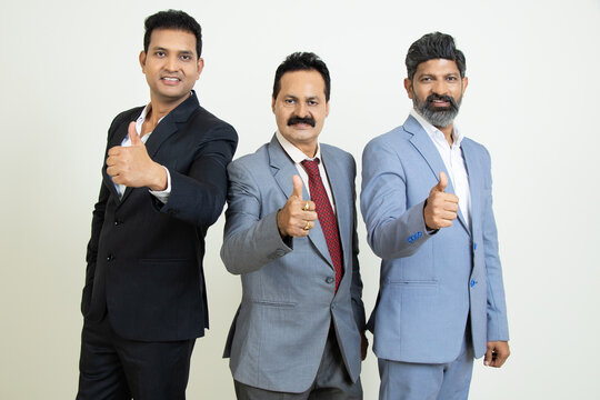 Group Of Positive Indian Business People Wearing Suit Doing Thumbs Up While Looking At Camera Isolated On White Studio Background. Corporate Concept.