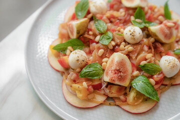 Top view of healthy salad with figs, apples, mints and tomatoes served with cheese on plate
