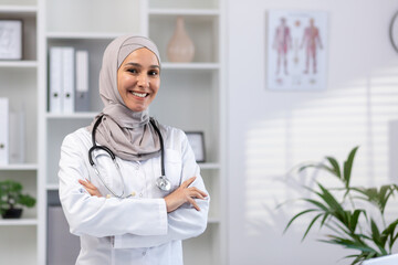 Portrait of young female doctor wearing hijab, Muslim woman smiling and looking at camera with arms...