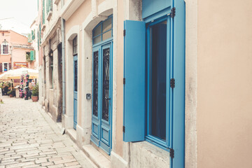 Old, colorful, shabby houses in the center of Rovinj, close-up on windows with blue shutters.