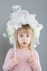 Portrait of adorable little girl in white flower hat on gray background