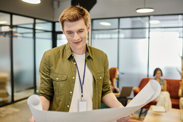 Obraz premium smiling manager looking at blueprint, businesswomen talking on blurred background in office