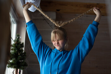 A young girl in a blue hoodie is messing with her braids on the eve of the new year