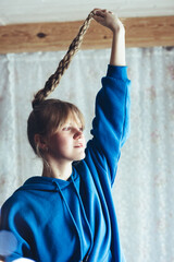 A young girl in a blue hoodie is messing with her braids on the eve of the new year