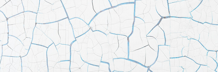 White peeling paint on the wall. Old concrete wall with cracked flaking paint. Weathered rough painted surface with patterns of cracks and peeling. High resolution texture for background and design.