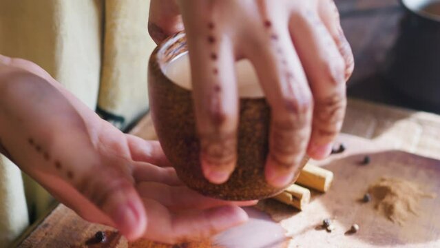 Indian woman hands taking wooden cup of masala chai tea. Close up.