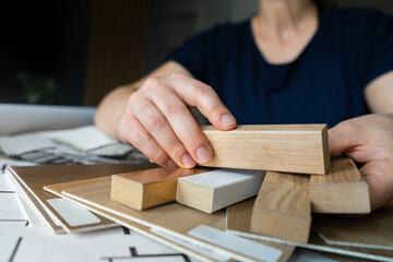 Female interior designer showing array of wooden slats lamella panels and wood floor or flooring samples to clients in a design studio. Woman showcasing an assortment of materials to her customers.