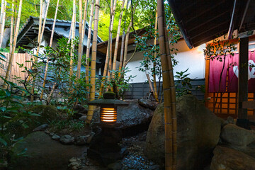 KUROKAWA ONSEN, JAPAN: ryokan garden with traditional stone lantern and bamboo grove, in one of Japan's most attractive hot spring towns, with luxury ryokan, bath houses, tourist shops and cafes - obrazy, fototapety, plakaty