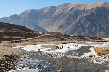 MAMBA, TIBET/CHINA: group of Tibetan kids play with sleds on frozen mountain stream, near Drigung Til monastery