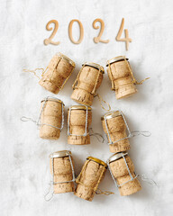 Minimal pattern New Year, xmas concept, wine corks from champagne sparkling wine and 2024 on white fur, bottle stoppers festive drinks, creative aesthetic still life, winter holidays, vertical