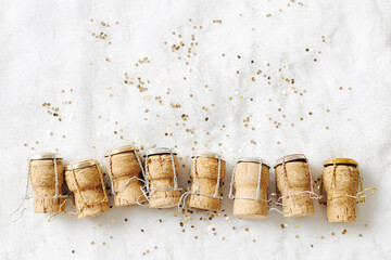 Aesthetic still life New Year, xmas background, wine corks from champagne sparkling wine on white fur as shiny snow, bottle stoppers festive drink, golden star sequins, winter holidays frame