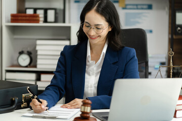 Female Legal counsel working with paperwork on his desk in office workplace working with laptopt computer. Justice and law concept.