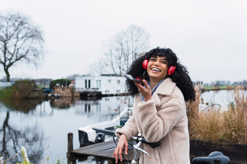 Obraz premium Beautiful woman with headphones and smartphone rides a bicycle listening to music. Active lifestyle, vacation, resting. Communication in social networks. Lifestyle.