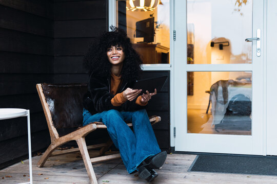 Beautiful happy woman sitting on terrace and using tablet