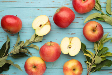 Ripe red apples with green leaves on blue wooden background. Top view.