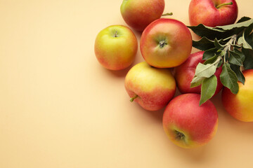 Ripe red apples with green leaves on beige background.