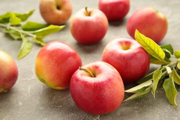 Group of red apples with their leaves on grey background